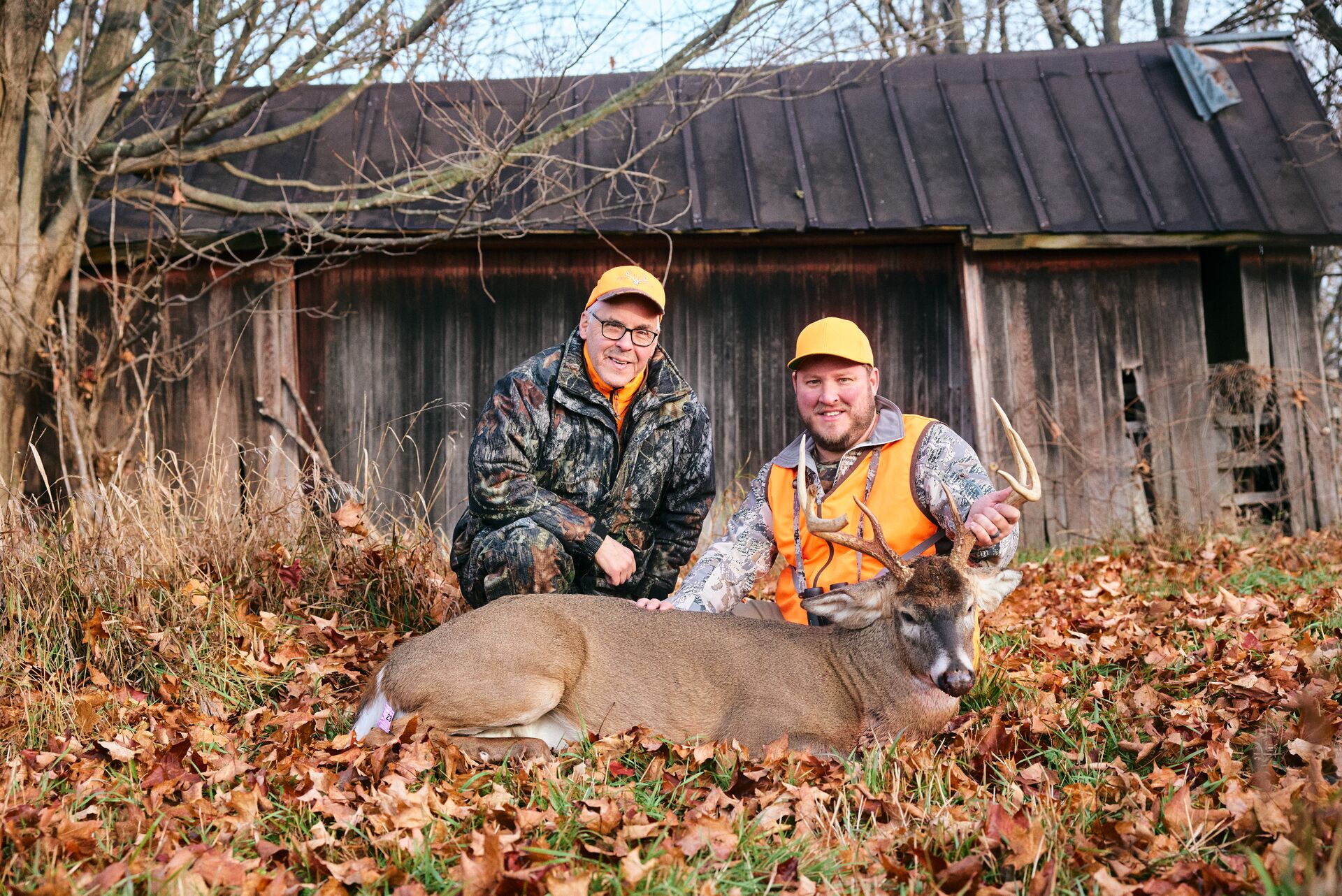 Two hunters pose with a deer kill on the ground, how I learn to hunt concept. 