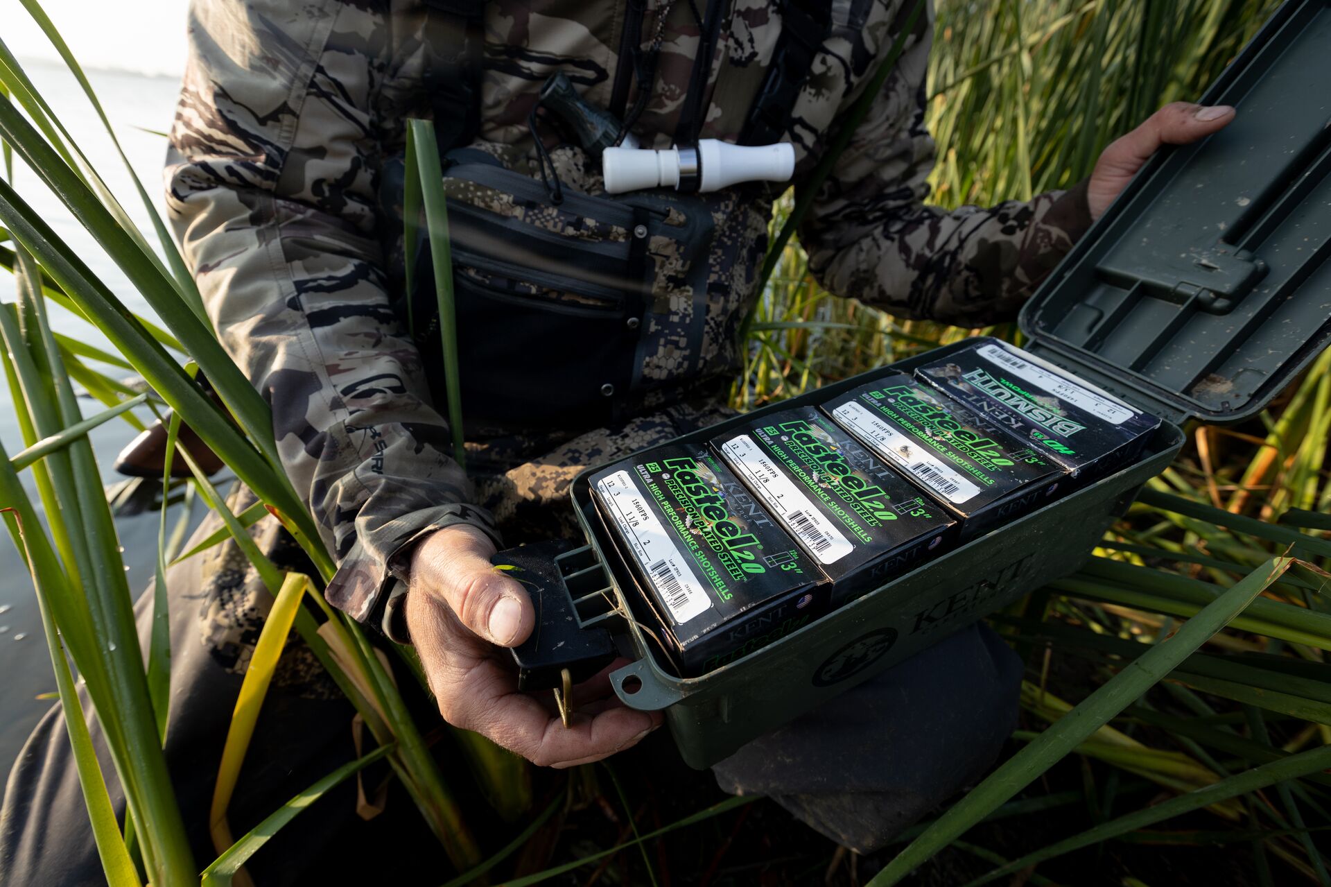 Close-up of a hunter holding an open box of shotgun shells, use the right ammo to avoid shotgun explosion concept. 