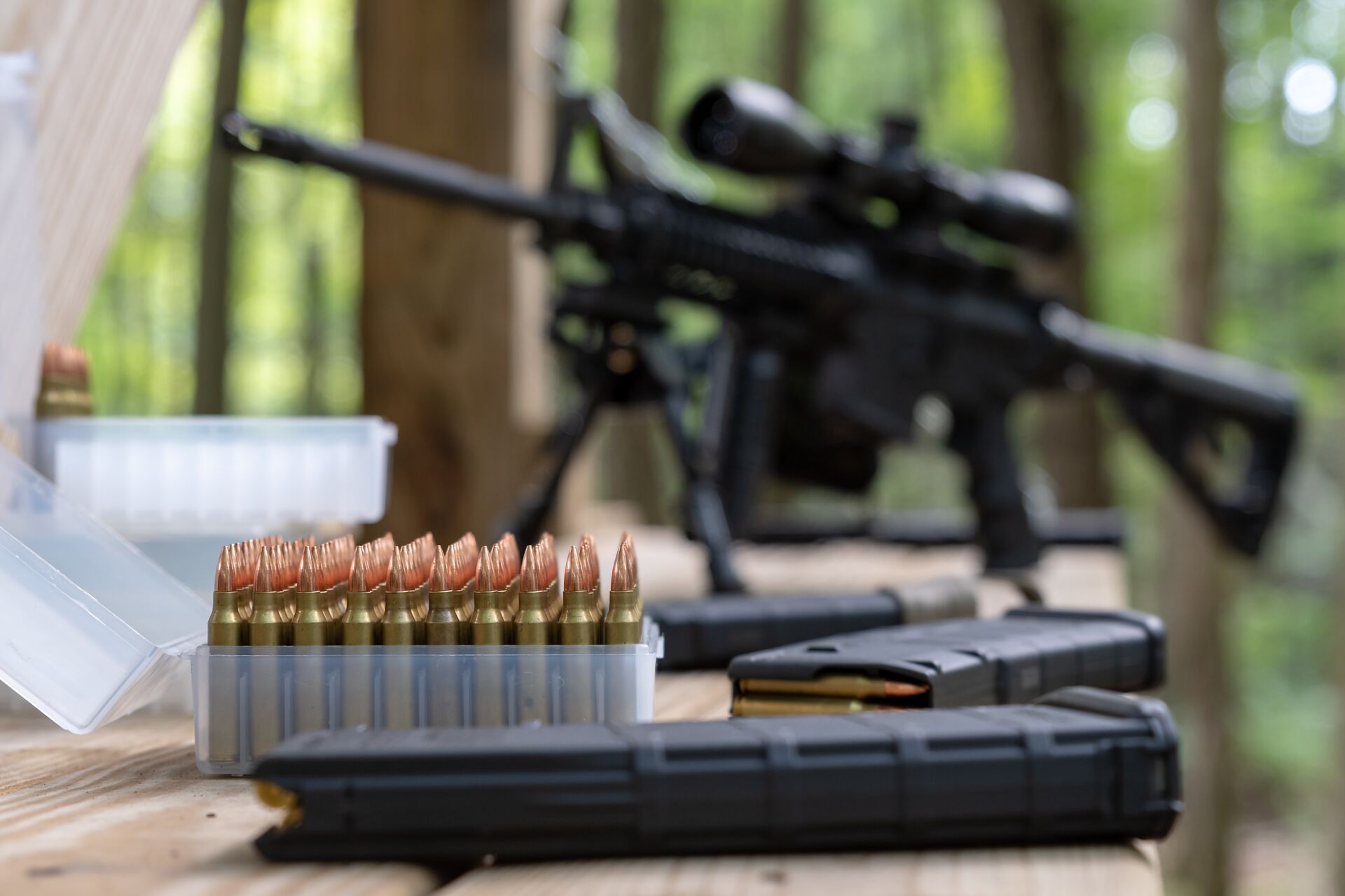 An AR-15 in the background of ammunition close-up, understanding gun calibers for hunting concept. 