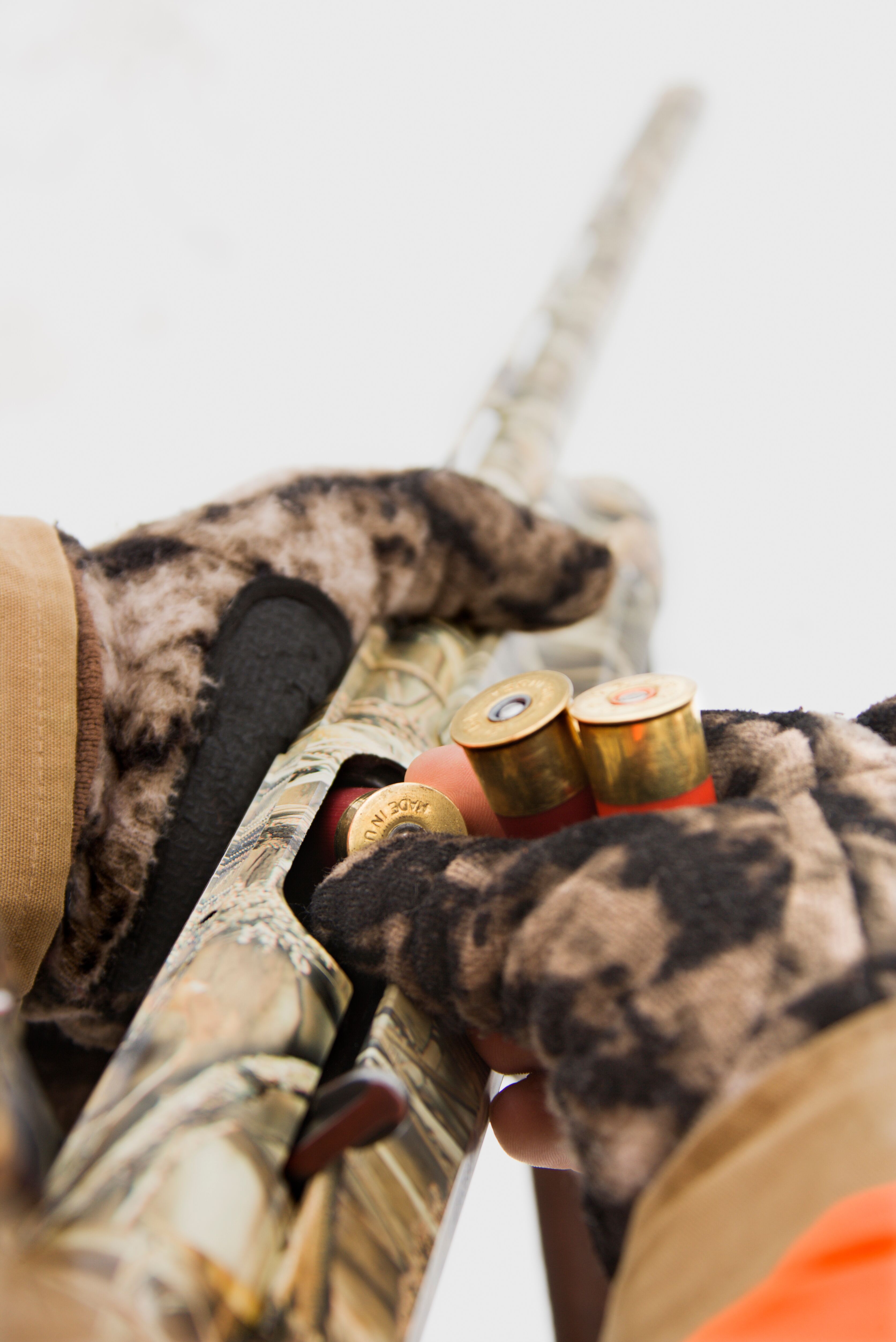 Close-up of hands loading shells into a camo shotgun, ready for open season hunting concept. 