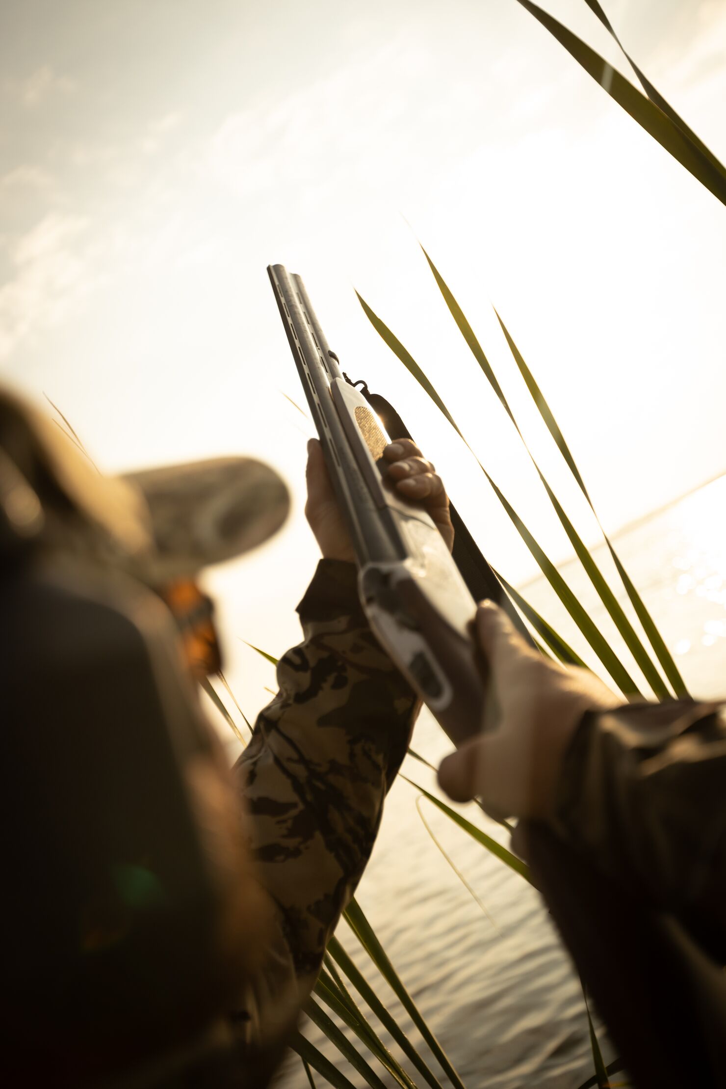 A hunter points a shotgun barrel at the sky, hunting with a shotgun concept. 