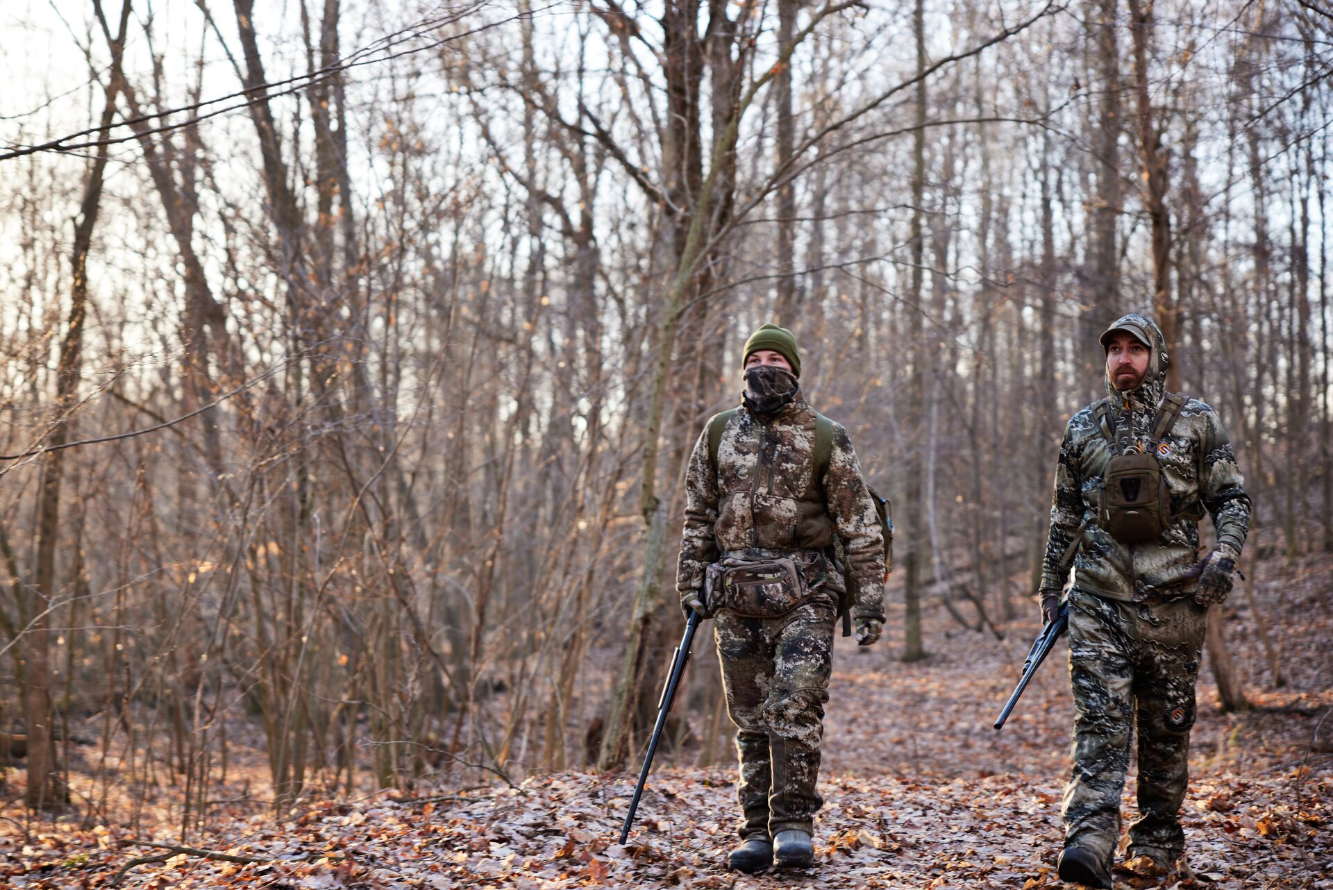 Two hunters walking next to each other, carrying firearms concept. 