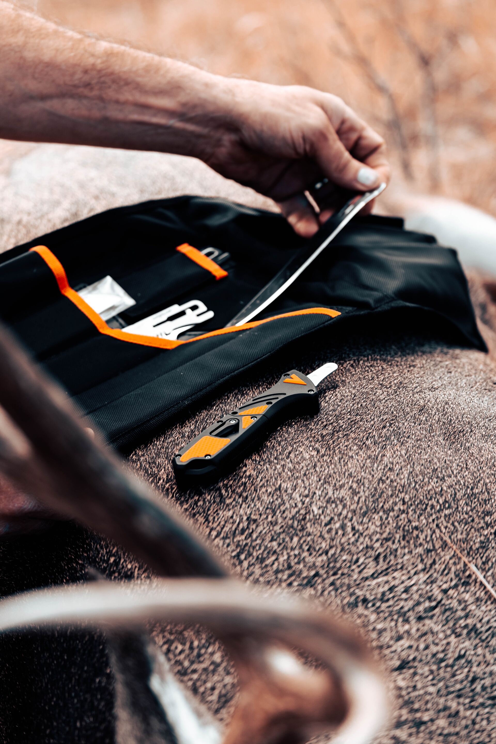 A hunter selects a knife for dressing a deer in the field. 