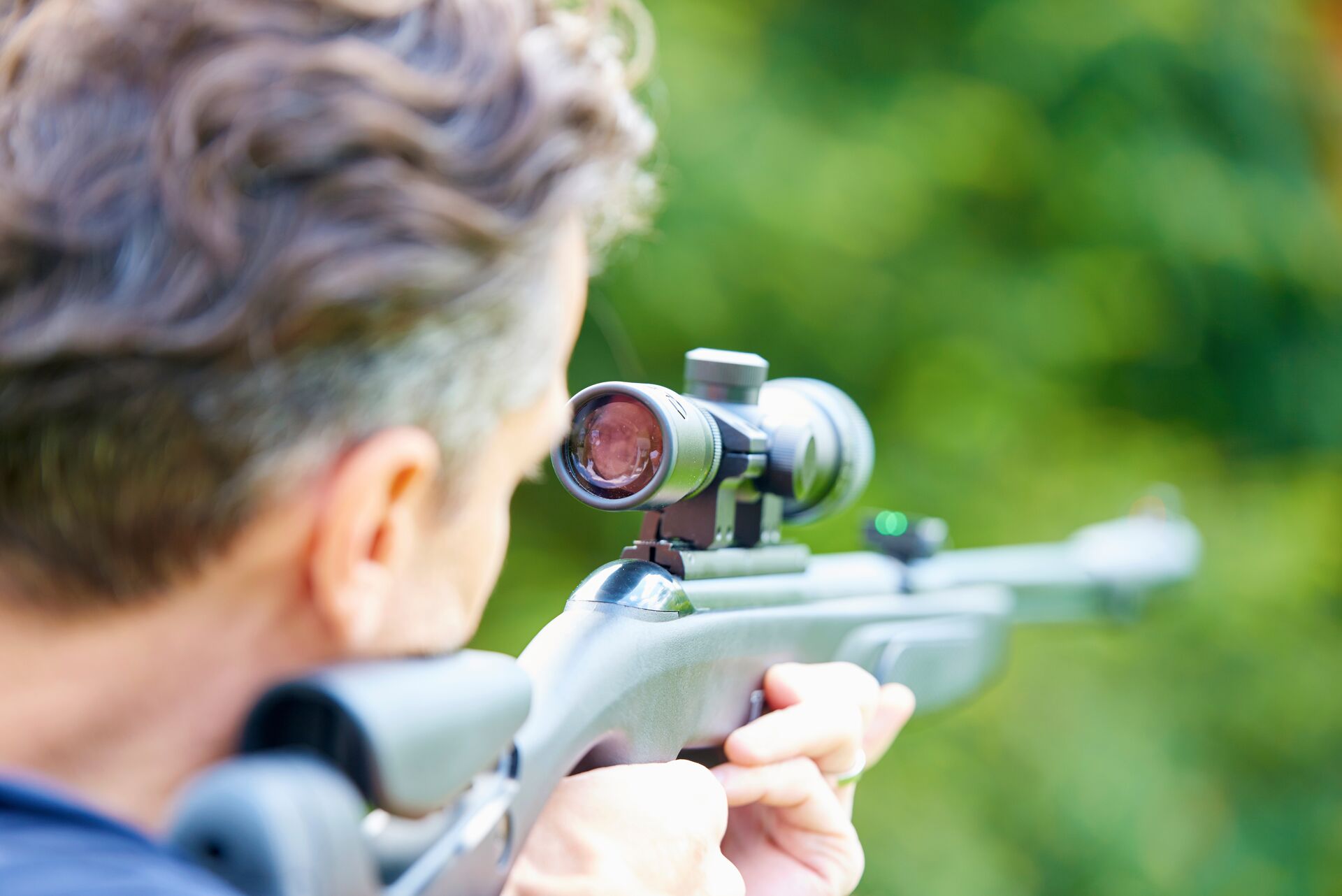 A hunter looks through scope on a rifle, sight alignment concept. 