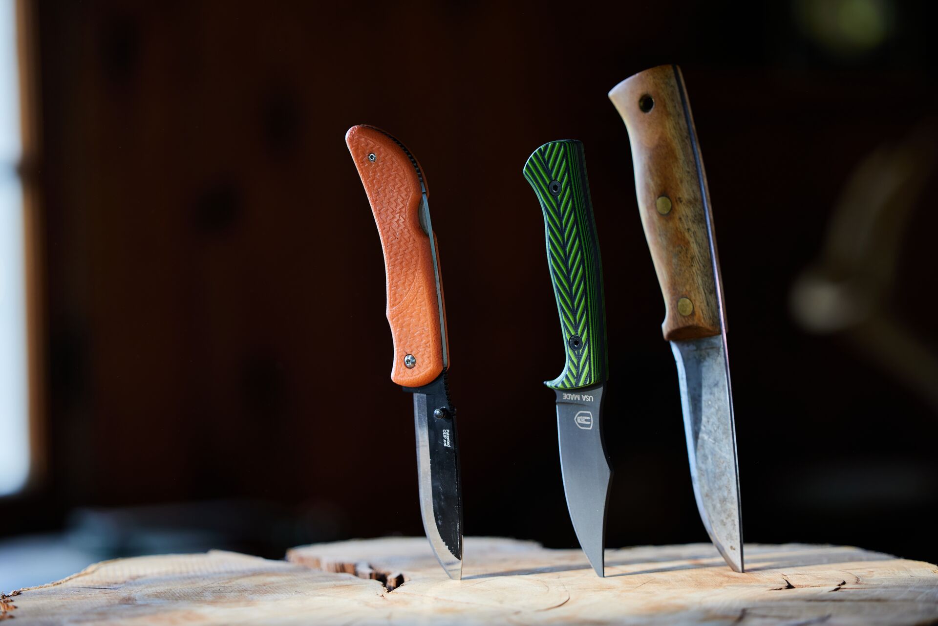 Three knives sticking into a tree stump, sharp knife for animal fleshing concept. 