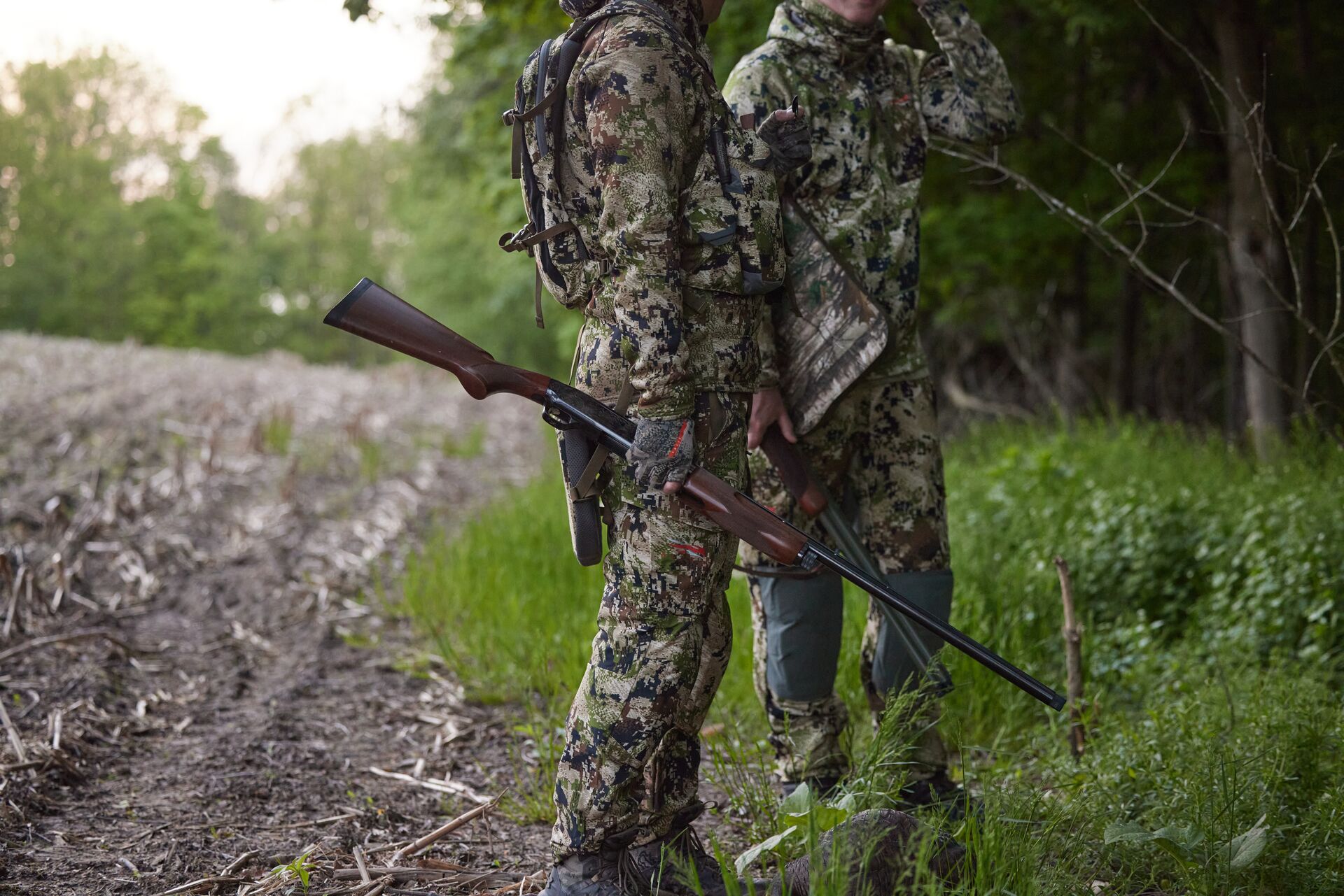 Two hunters in camo hold shotguns, when to use improved cylinder choke concept. 