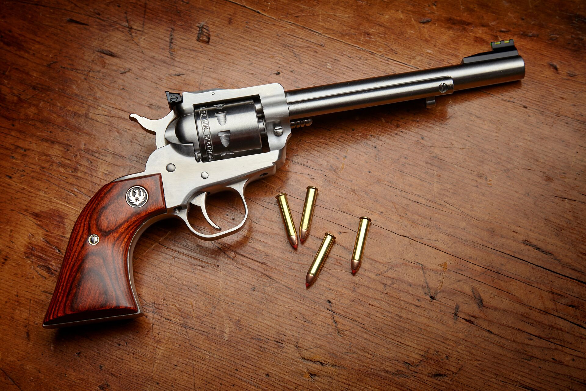 A single action revolver next to ammunition on a table. 