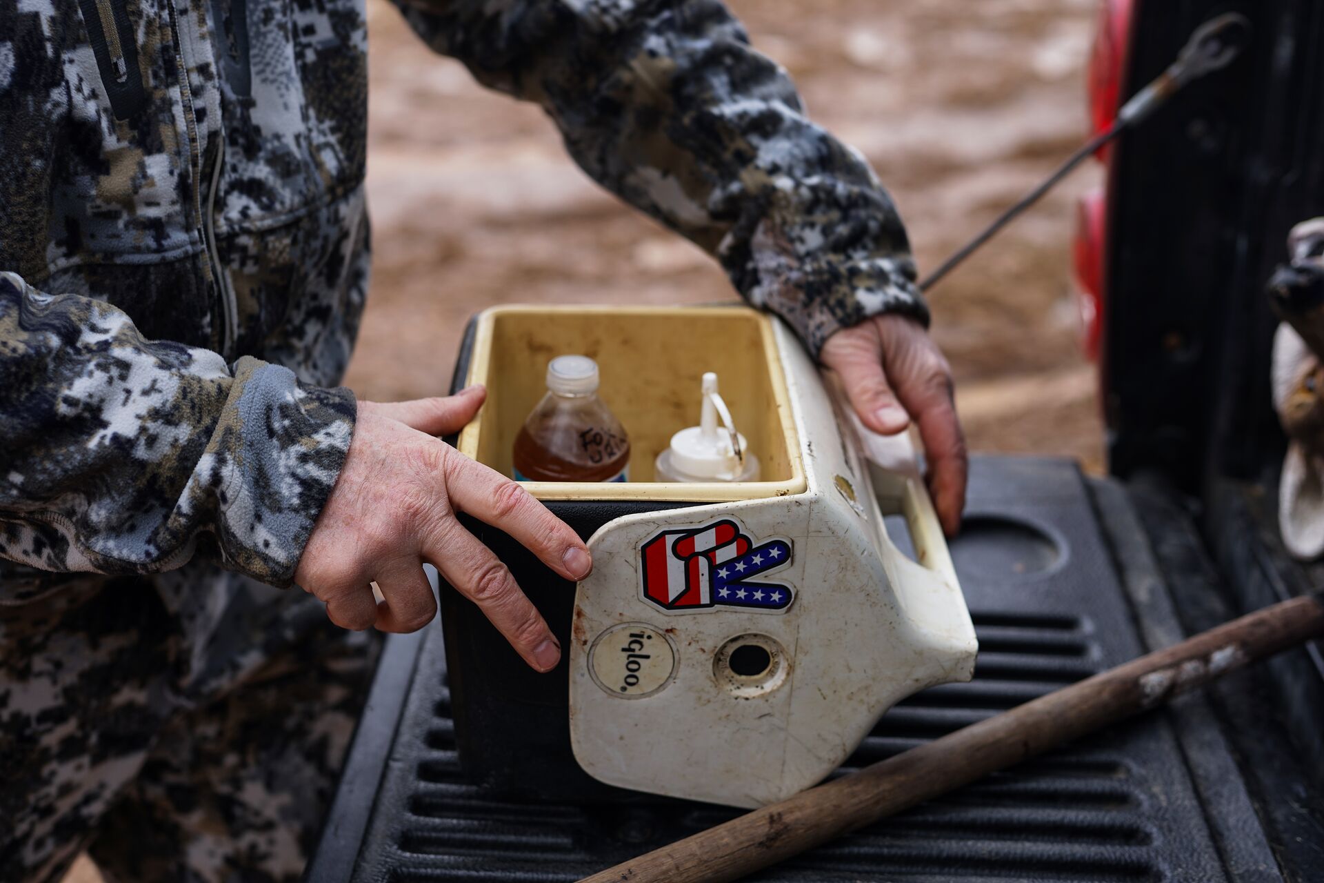 A hunter with a cooler containing coyote lure.