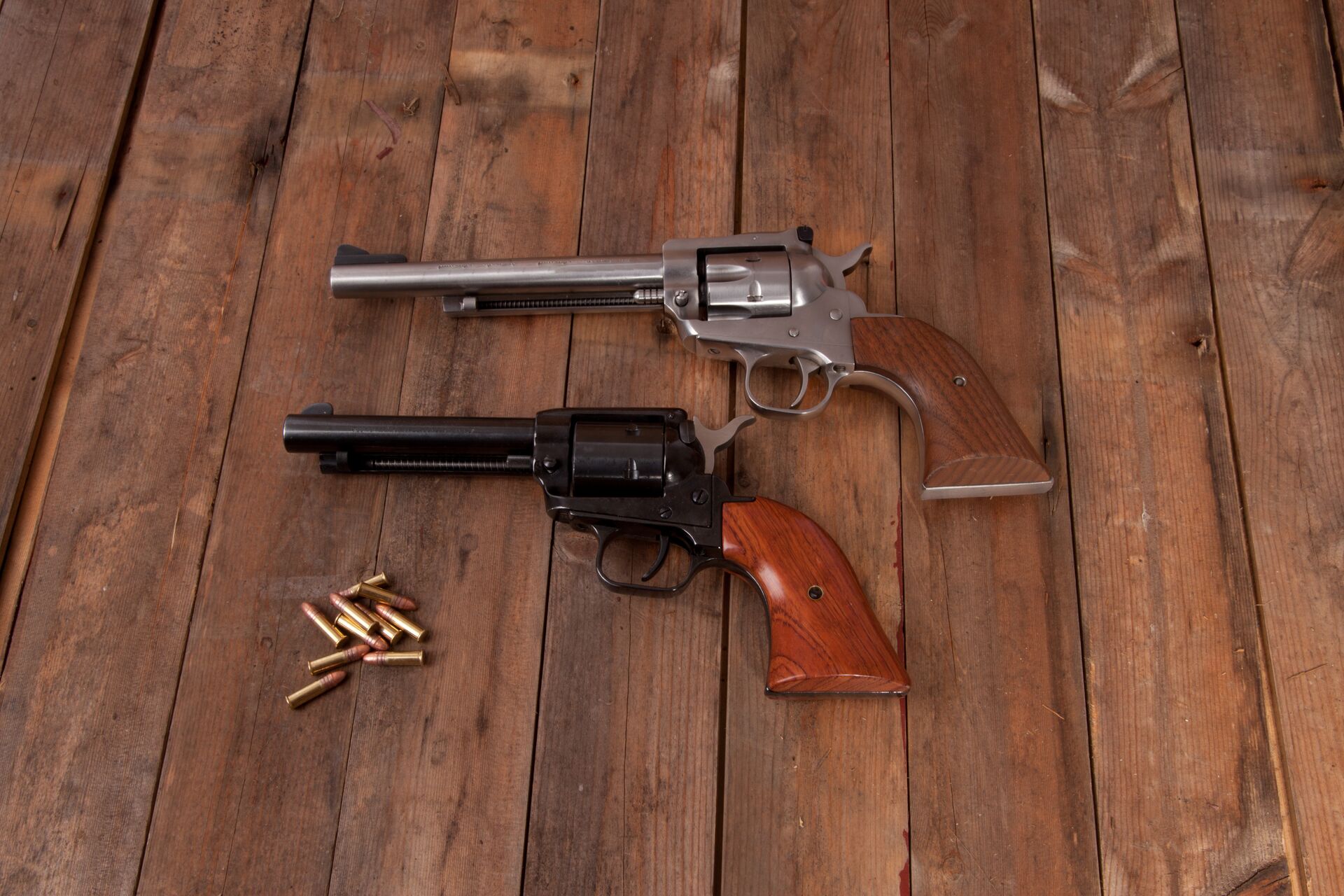 Two revolvers on a table next to ammunition, parts of a revolver concept. 