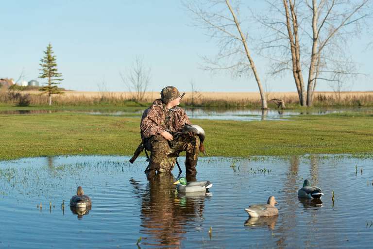 A young hunter sits with waterfowl decoys, youth hunting age concept. 