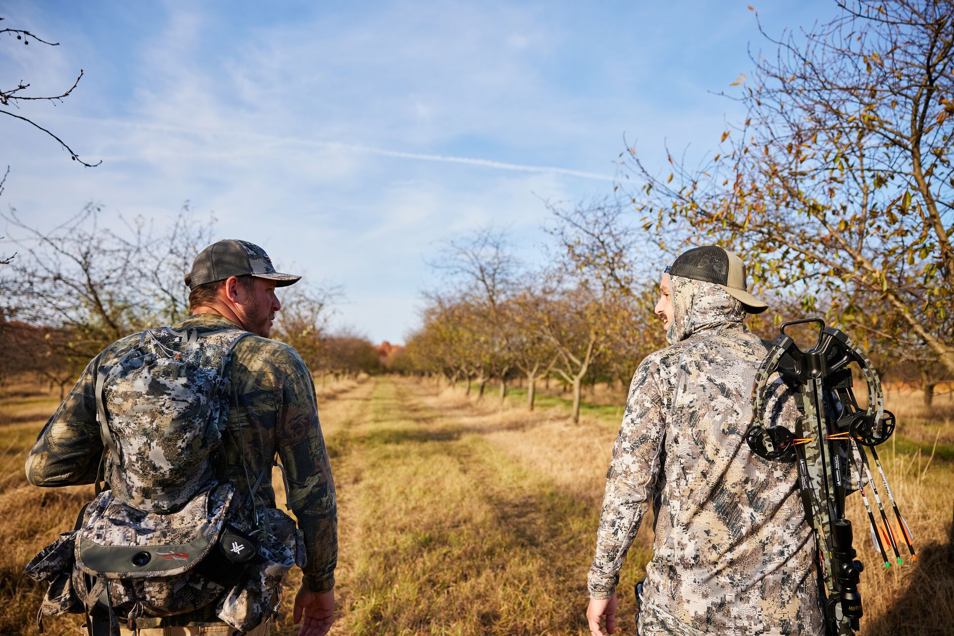 Two hunters in camo walk through a field, what is an apprentice hunting license concept. 