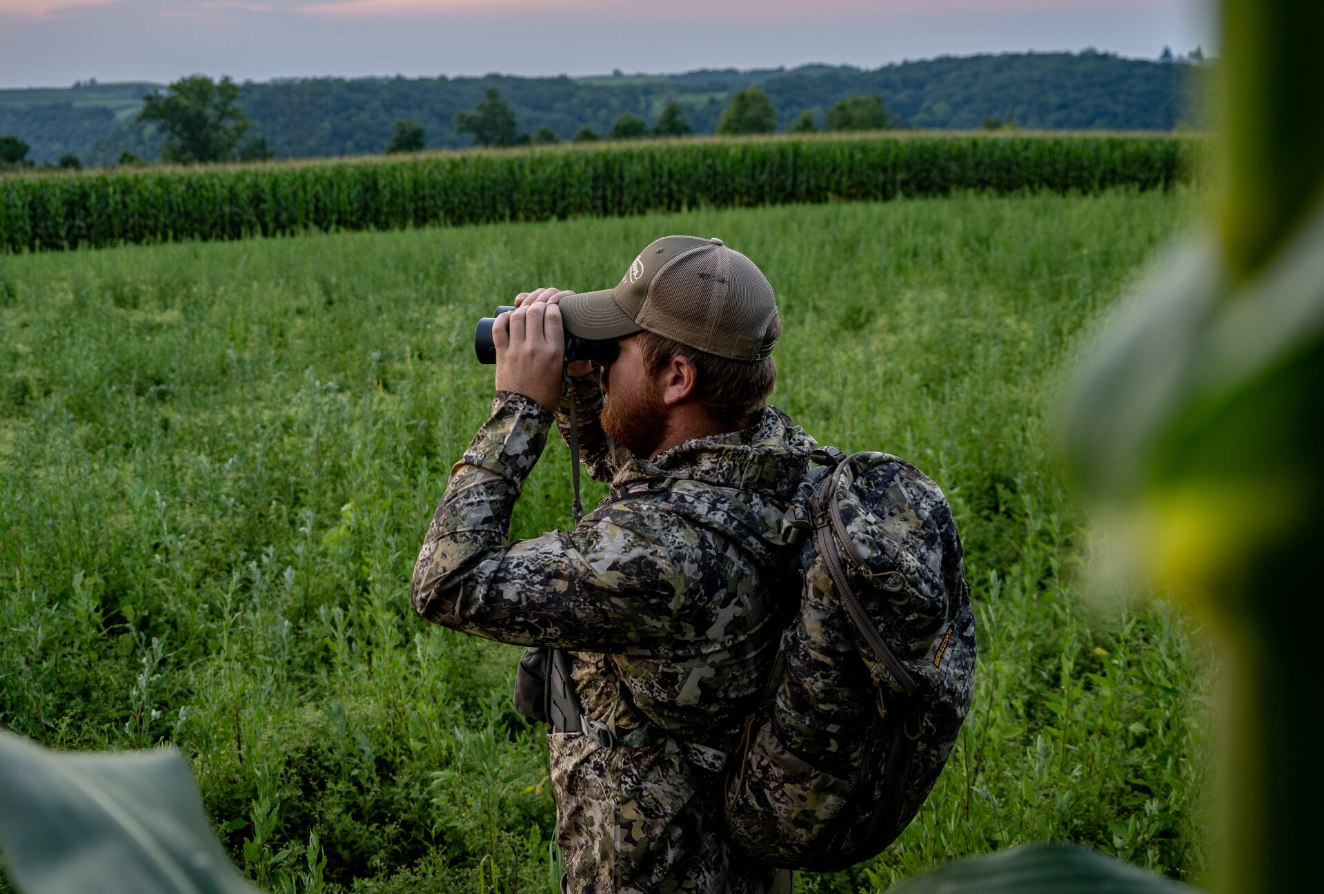 A hunter uses binoculars in the field, should I learn to hunt concept. 